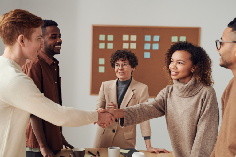 Two colleagues shaking hands in team meeting - psychological safety