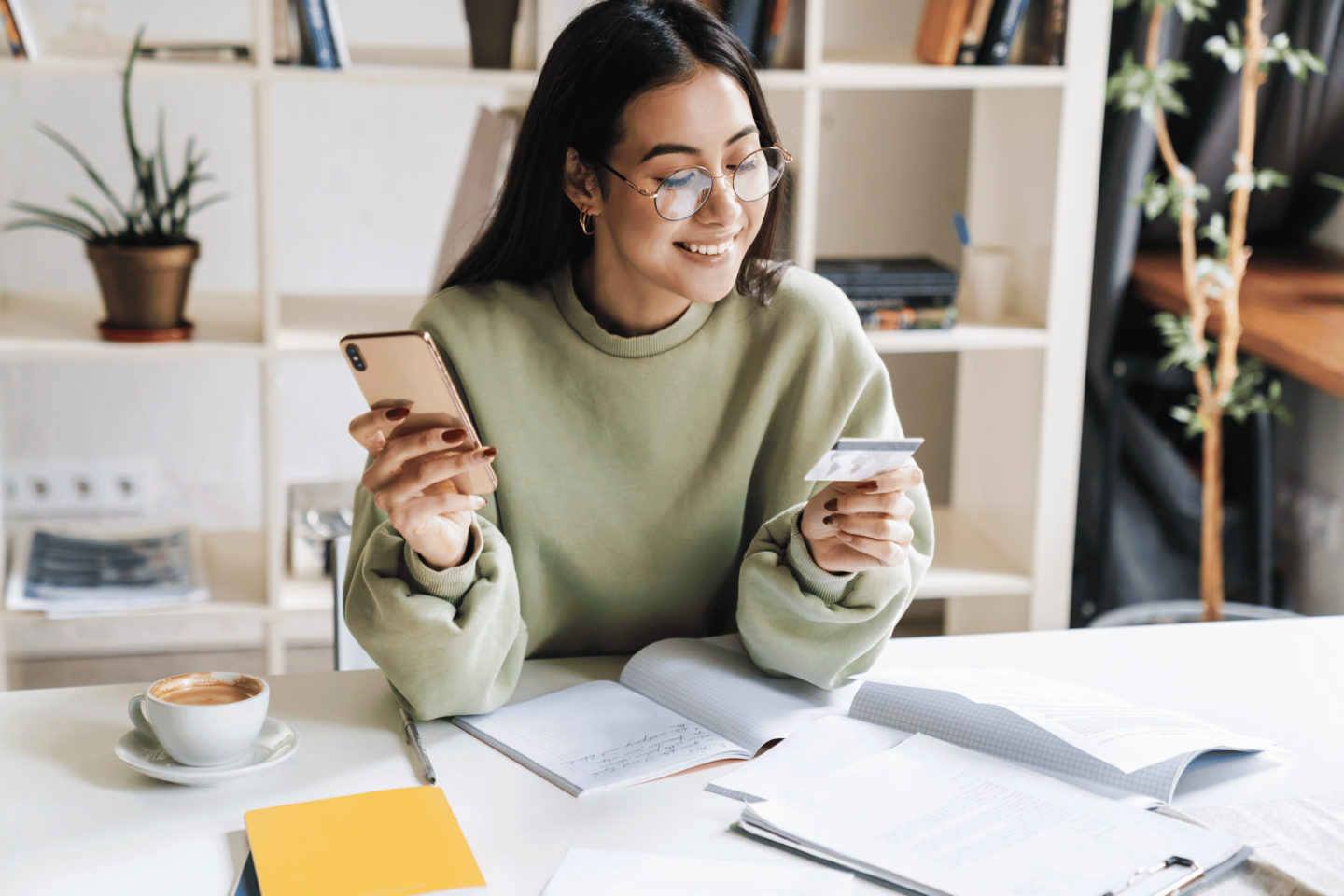 Woman smiling looking at credit card and holding phone